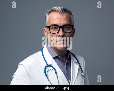 Zuversichtlich Chefarzt auf grauem Hintergrund, Medizin und Gesundheitswesen Konzept posing Stockfoto