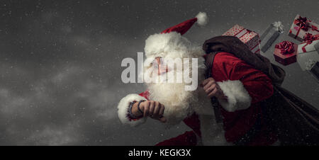 Santa claus läuft und die Weihnachtsgeschenke: Er ist spät und verlieren Geschenke aus seinem Sack. Stockfoto