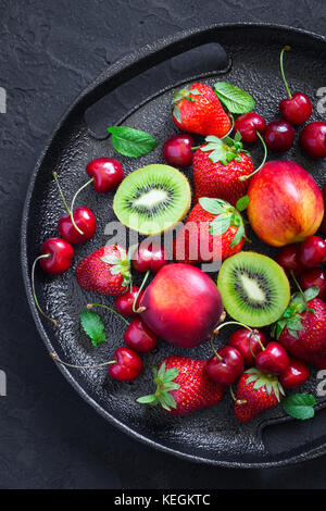Schwarz Teller mit verschiedenen Sommer Beeren und Früchten. Top View Stockfoto