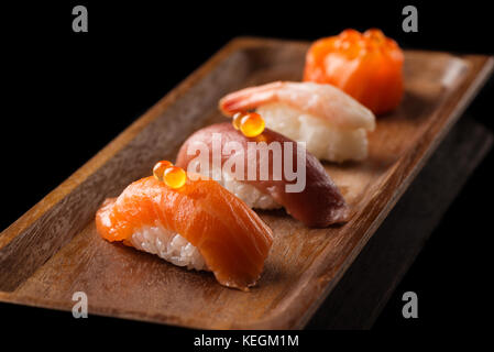 Nahaufnahme der sashimi Sushi auf Holzplatte auf schwarzem Hintergrund isoliert. asiatisches Restaurant Menü Stockfoto