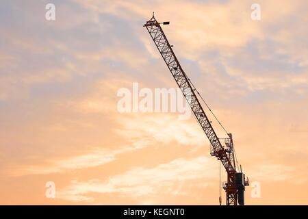 Industriellen Hintergrund, große Baustelle, darunter mehrere Kran mit goldenen Himmel und Sonnenaufgang am Morgen. Stockfoto