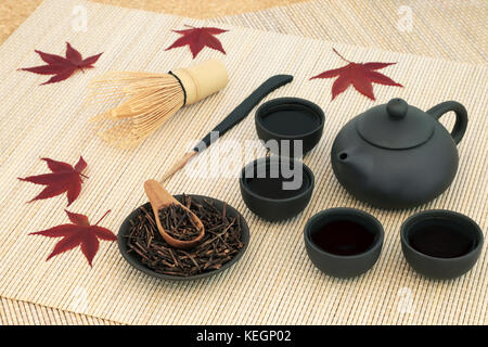 Japanische kuchika geröstete Zweig Grüner Tee mit Teekanne und Tassen, Rührer, Schneebesen und Ahornblätter auf Bambus Hintergrund. hat viele gesundheitliche Vorteile. Stockfoto