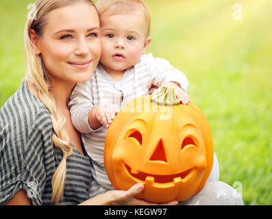 Portrait von eine nette Mutter mit ihrem kleinen Sohn an der Hand lustig geschnitzten Kürbis, Feier der traditionellen amerikanischen Feiertag, happy halloween da Stockfoto