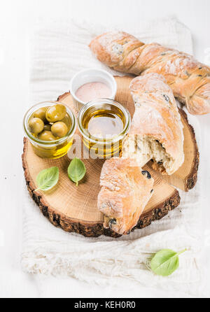 Frisches ciabatta Brot, mediterrane Oliven und frisches Öl vrgine mit Basilikum auf Holzbrett mit weißem Hintergrund, selektive konzentrieren. Stockfoto