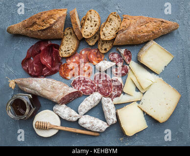 Fleisch und Käse Vorspeise Auswahl oder Wein Snack. Vielzahl von italienischen Käse, Salami, Bresaola, Baguette und Honig auf über grau-blauen Beton zurück Stockfoto