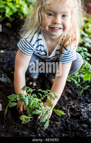 Kaukasische Mädchen posiert mit Pflanze im Garten Stockfoto