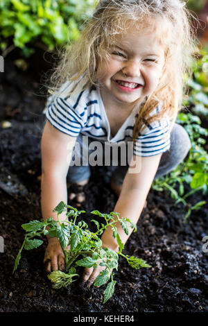 Kaukasische Mädchen posiert mit Pflanze im Garten Stockfoto