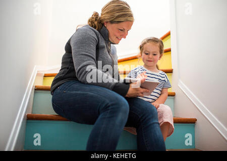 Kaukasische Mutter und Tochter mit digitalen Tablet auf Treppe Stockfoto