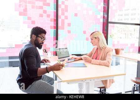 Kreative Geschäftsleute, die Technologie am Tisch einsetzen Stockfoto