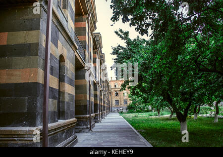 Fassade eines alten Gebäudes der mehrfarbigen Tuff mit geschnitzten Gesimse und Loggien mit Blick auf einen Innenhof mit Obst Garten Stockfoto