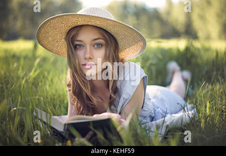 Kaukasische Frau liegt im Gras Buch zu lesen Stockfoto