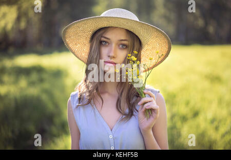 Kaukasische Frau trägt Hut mit Wildblumen Stockfoto