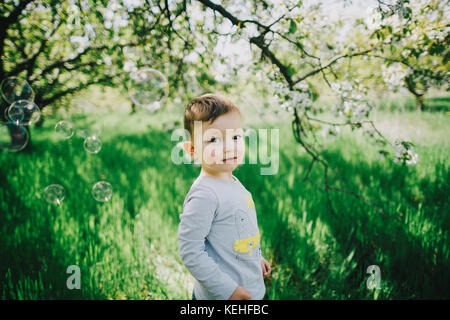 Blasen schwimmend nahe kaukasischen Jungen im Feld in der Nähe von Baum Stockfoto