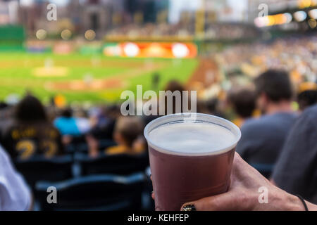 Hand der Frau, die eine Tasse Bier im Baseballstadion hält Stockfoto