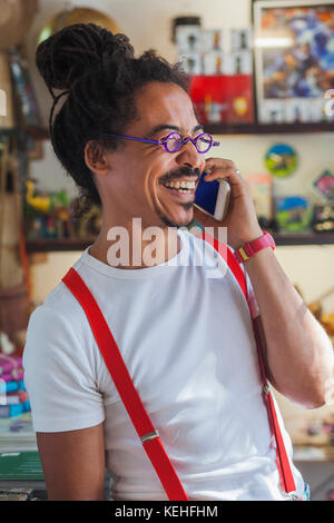 Lachende gemischte Rasse Mann trägt Hosenträger reden auf Handy Stockfoto