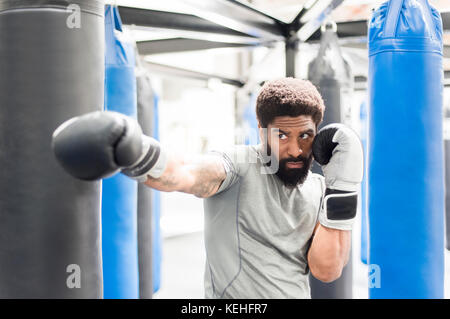 Portrait des schwarzen Mannes mit Boxhandschuhen in der Turnhalle Stockfoto
