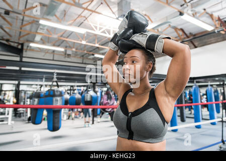 Schwarze Frau, die mit erhobenen Armen im Boxring ruht Stockfoto