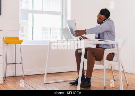 Schwarzer Geschäftsmann im Gespräch auf Handy und Lesen Notizblock Stockfoto