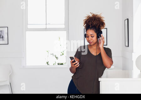 Mixed Race Frau hört Handy mit Kopfhörer Stockfoto