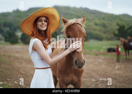 Lächelnde Frau streichelt Pferd Stockfoto