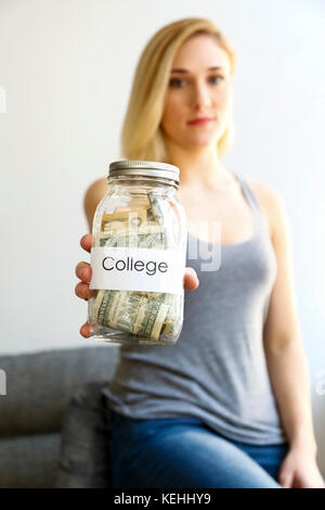 Kaukasische Frau zeigt Glas Geld für die Hochschule Stockfoto