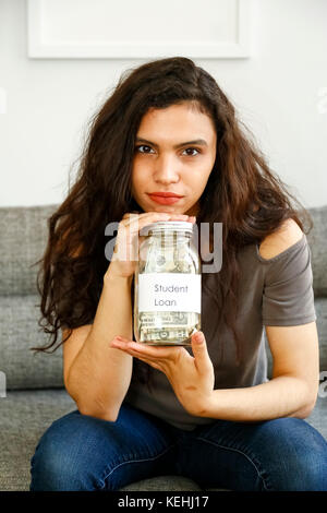 Portrait der gemischten Rasse Frau hält Glas Geld für Studenten Darlehen Stockfoto