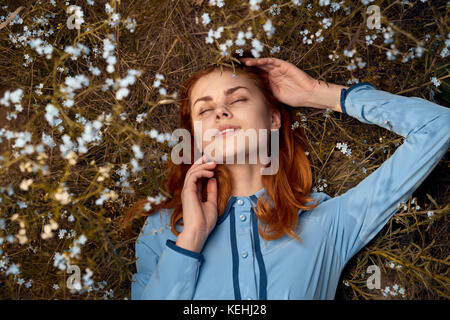 Kaukasische Frau, die im Feld der Wildblumen liegt Stockfoto