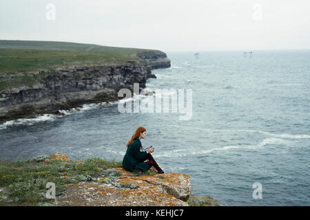 Kaukasische Frau untersucht Kamera in der Nähe des Ozeans Stockfoto