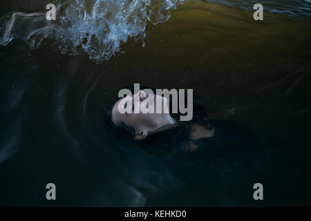 Kaukasische Frau schwimmt im Meer mit geschlossenen Augen Stockfoto