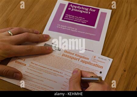 Blick auf die Hände des Menschen Ausfüllen britischen Reisepass Antragsformular auf Tabelle mit anweisende Broschüre Stockfoto