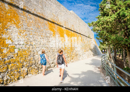 Touristen vorbei an den riesigen Mauern der Fortica über der Stadt Hvar Stockfoto