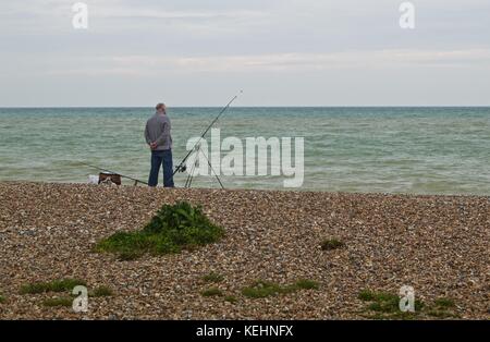 Älterer Mann angeln im Meer vom Strand, Littlehampton, Großbritannien Stockfoto