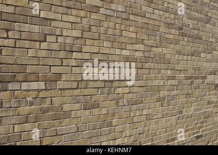 Nahaufnahme eines schrägen Blickes auf einen hell sonnendurchfluteten, beige und bräunlichen Hintergrund moderner Ziegelwände. Stockfoto