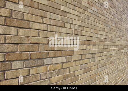 Nahaufnahme eines schrägen Blickes auf einen hell sonnendurchfluteten, beige und bräunlichen Hintergrund moderner Ziegelwände. Stockfoto