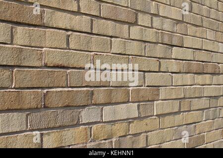 Nahaufnahme eines schrägen Blickes auf einen hell sonnendurchfluteten, beige und bräunlichen Hintergrund moderner Ziegelwände. Stockfoto