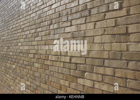 Nahaufnahme eines schrägen Blickes auf einen hell sonnendurchfluteten, beige und bräunlichen Hintergrund moderner Ziegelwände. Stockfoto