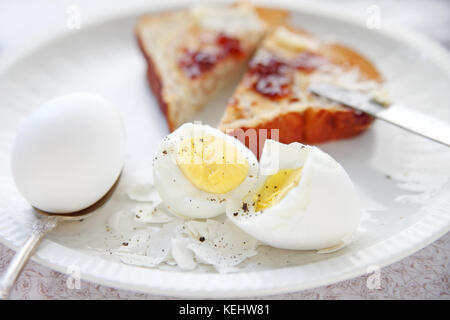 Zwei gekochte Eier, eine Hälfte - geschält und auseinander gebrochen, mit Toast mit Marmelade und Butter verteilt, in Dreiecke schneiden Stockfoto
