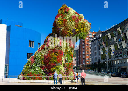 Touristen im Puppy by Jeff Koons Blumenkunst in Hundehühe im Guggenheim Museum by Silken Gran Hotel Domine in Bilbao, Spanien Stockfoto