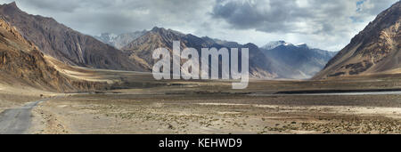 Panorama Foto hohe Berge Tal: Breite braune Hügel Canyon, unter grauen Abend Himmel mit Wolken, Nebel liegt auf den Pisten, Tibet. Stockfoto