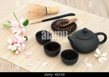 Kuchika japanische gerösteten grünen Zweig Tee mit Teekanne und Tassen, Rührer, Schneebesen und blühen Blumen auf Bambus Hintergrund. hat viele gesundheitliche Vorteile. Stockfoto