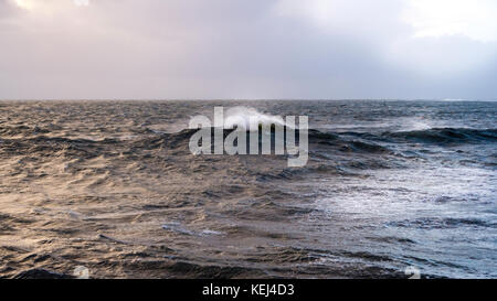 Sonnenlicht bricht durch die schweren Wolken. Dramatische Küstenansicht am frühen Morgen als der Atlantische Sturm Brian im Süden Cornwall, Großbritannien erreicht Stockfoto