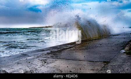 Sonnenlicht bricht durch die schweren Wolken. Dramatische Küstenansicht am frühen Morgen als der Atlantische Sturm Brian im Süden Cornwall, Großbritannien erreicht Stockfoto