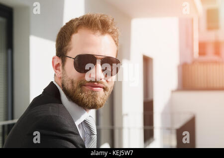 Schöne bärtige Geschäftsmann in Sonnenbrille stehen auf dem Balkon Stockfoto