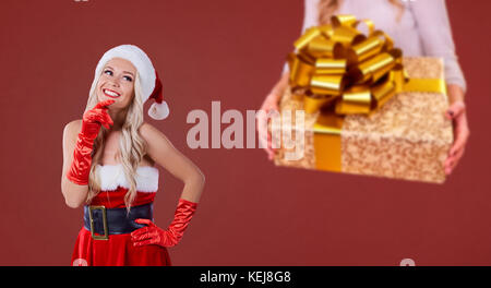 Ein Mädchen in der Santa Kostüm träumt von einem Geschenk für Weihnachten. Stockfoto