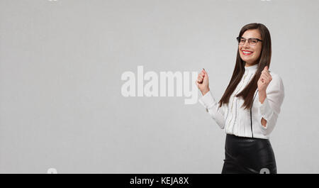 Business Frau genießt Erfolg auf einem grauen Hintergrund für Text. Stockfoto