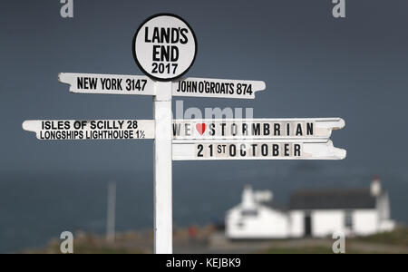 "We love Storm Brian" ist auf dem Lands End Wegweiser in Cornwall zu sehen, als Storm Brian das Vereinigte Königreich mit Winden von bis zu 70 km/h trifft, die Küstengebiete durchbrechen. Stockfoto