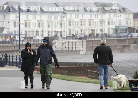 In Porthcawl laufen die Menschen entlang der Küste, während Sturm Brian Großbritannien mit Windgeschwindigkeiten von bis zu 70 km/h trifft, die Küstengebiete treffen. Stockfoto