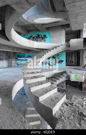 Eine Wendeltreppe aus Beton in einem unvollendeten, verlassenen Gebäude Stockfoto