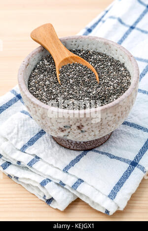 Nahrhafte Chia Samen in Keramik Schüssel mit Löffel aus Holz für Ernährung Lebensmittel Zutaten. Stockfoto