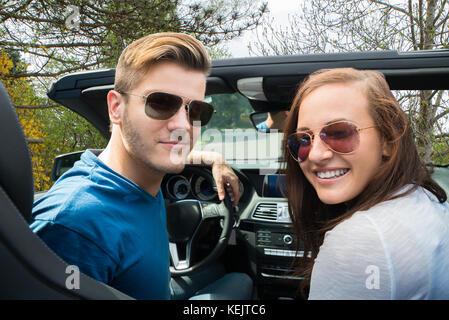 Glückliches Paar sitzen in einem Auto mit Sonnenbrille Stockfoto
